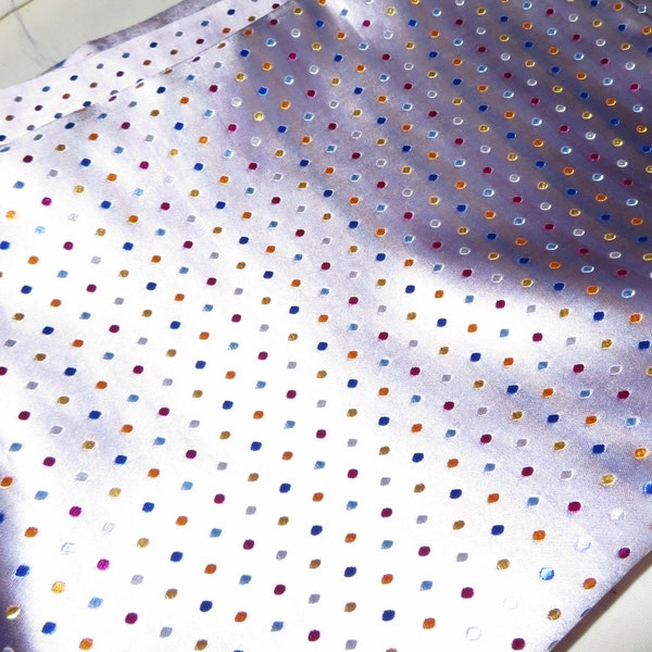 Light pinkish lavender satin fabric with colorful specks embroidered in it.