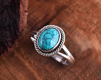 May include: A silver ring with a turquoise stone set in a rope-like design.