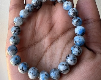 May include: A blue and white speckled stone beaded bracelet. The bracelet is made of round beads and is approximately 8 inches in length.