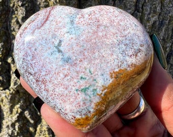 May include: A heart-shaped polished stone with a white, brown, and green mottled pattern.