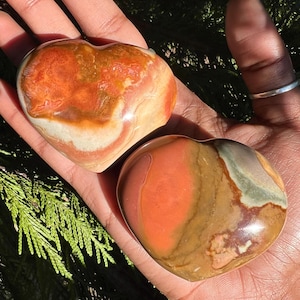 May include: Two heart-shaped polished stones with brown, red, and white swirling patterns.