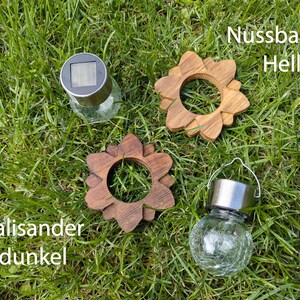 May include: Three solar powered lights with different wood accents. The lights are in the shape of a flower with a glass globe. The wood accents are labeled "Nussbaum Hell", "Palisander dunkel", and "Palisander dunkel".
