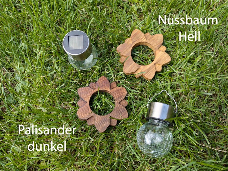 May include: Three solar powered lights with different wood accents. The lights are in the shape of a flower with a glass globe. The wood accents are labeled "Nussbaum Hell", "Palisander dunkel", and "Palisander dunkel".