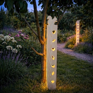 Könnte beinhalten: Gartenleuchte aus Holz mit einer Eichhörnchen-Silhouette oben und blattförmigen Aussparungen. Das Licht steht neben einem Baum in einem Garten, mit einem zweiten Licht im Hintergrund. Die Lichter beleuchten den Gartenweg.
