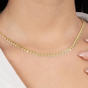 May include: A gold necklace with a delicate chain and small round charms hanging from it.
