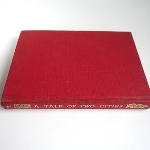 May include: A red hardcover book with the title "A Tale of Two Cities" in gold lettering on the spine.