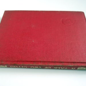 May include: A red hardcover book with the title "A Tale of Two Cities" printed in gold lettering on the spine.