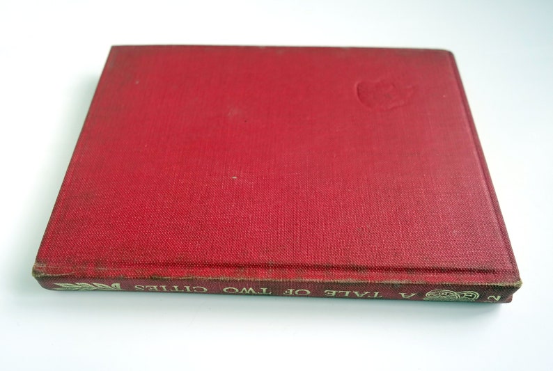 May include: A red hardcover book with the title "A Tale of Two Cities" printed in gold lettering on the spine.
