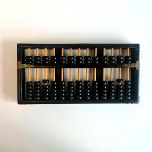 May include: A traditional abacus featuring a black wooden frame and black beads. The beads are strung on wooden rods. This calculating tool is often used in education and mathematics. The abacus is a classic educational toy, often used in schools.