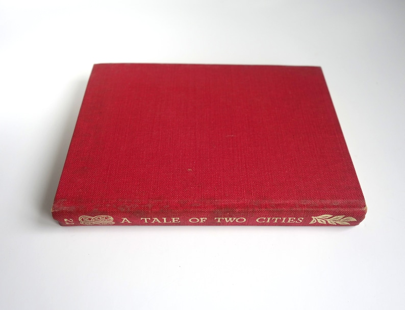 May include: A red hardcover book with the title "A Tale of Two Cities" in gold lettering on the spine.