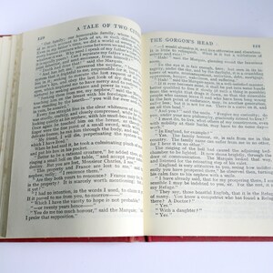 May include: An open book with a red cover. The pages are open to a chapter titled "The Gorgon's Head" from the novel "A Tale of Two Cities". The text on the page discusses the family's history and the curse of the land.