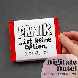 Könnte beinhalten: Ein weißer Schokoladenriegel-Wrapper mit schwarzem Text, der "Panik...ist keine Option. Du schaffst das!" lautet. Der Wrapper ist an den Rändern rot und wird von einer Hand gehalten.