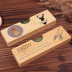 May include: Two wooden bottle openers with spirit levels. One has a deer head graphic and the name "Davine". The other says "DADDY" with a message and a hand-holding graphic. A Father's Day gift.