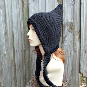 May include: Black knitted hat with a long pointed hood and a long scarf attached. The hat is on a mannequin head.