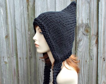 May include: Black knitted hat with a long pointed hood and a long scarf attached. The hat is on a mannequin head.