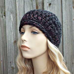Puede incluir: Un gorro de punto de color negro y rosa con un ajuste holgado. El gorro está hecho con un hilo grueso y tiene un patrón de punto simple.