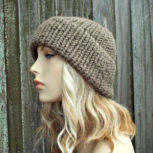 May include: A brown knitted beanie hat with a slouchy fit. The hat is made of a soft, textured yarn and has a simple, classic design.