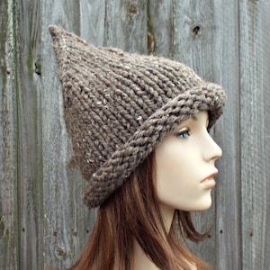 May include: A brown knitted hat with a pointed crown and a folded brim. The hat is made of a chunky yarn and has a rustic look.