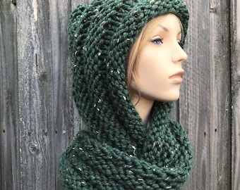 May include: A dark green hooded cowl scarf with a chunky knit texture. The scarf is made with a yarn that has a subtle fleck of white throughout.
