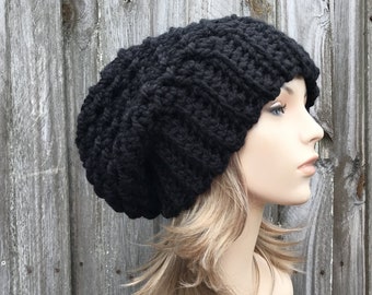 Op de afbeelding: Een zwarte, slouchy beanie muts gemaakt van dik garen. De muts is gebreid met een textuurpatroon.