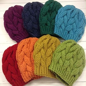 Peut inclure: Un ensemble de dix bonnets en tricot de différentes couleurs, dont le rouge, l'orange, le jaune, le vert, le bleu et le violet. Les bonnets sont tous faits avec un motif en tricot torsadé.