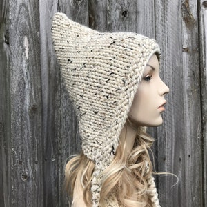 May include: A white knitted hooded hat with a long pointed tip. The hat has a speckled texture and is made with a thick yarn.