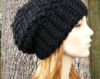 Op de afbeelding: Een zwarte gebreide beanie met een slouchy pasvorm. De muts is gemaakt van dik garen en heeft een eenvoudig ontwerp.