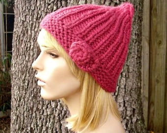 Puede incluir: Un gorro de punto rosa con un detalle de flor. Este es un patrón, no el artículo terminado. Esta lista es un tutorial de bricolaje para hacer tu propio gorro.