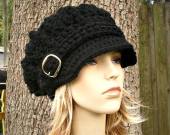 May include: A black crocheted newsboy cap with a gold buckle. The cap has a wide brim and a slouchy fit.