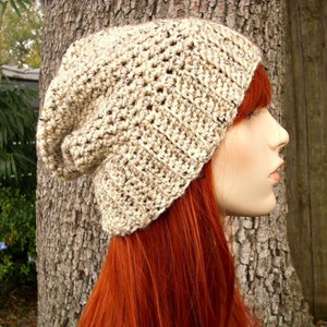 May include: A slouchy beanie hat in a beige and brown speckled yarn. The hat is crocheted and has a loose, slouchy fit.