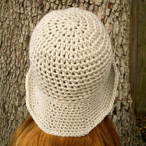 May include: A crocheted hat in a light beige color. The hat has a wide brim and a rounded crown.