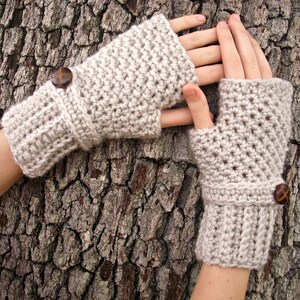 A pair of crochet fingerless mittens in a soft beige.