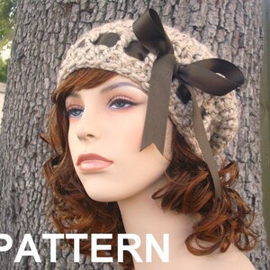 May include: A crocheted beige beanie with a brown satin ribbon bow. The beanie has a unique design with holes and a textured pattern.