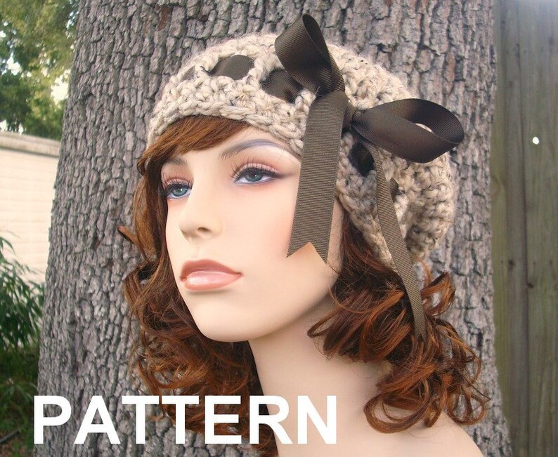 May include: A crocheted beige beanie with a brown satin ribbon bow. The beanie has a unique design with holes and a textured pattern.