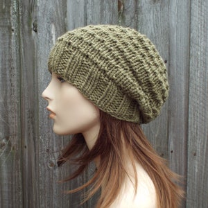 Puede incluir: Un gorro de punto verde con un ajuste holgado. El gorro está hecho con un patrón de punto texturizado.