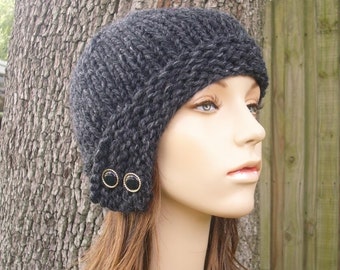May include: A gray knitted cloche hat with two black buttons on the side.