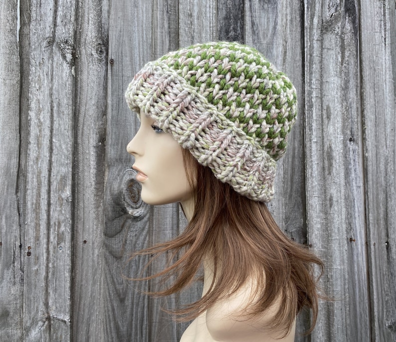 May include: A knitted beanie hat with a green and pink color pattern. The hat is made with a chunky yarn and has a slouchy fit.
