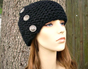 May include: A black knitted beanie with a slouchy fit and silver-toned decorative buttons. The beanie is worn on a person's head.