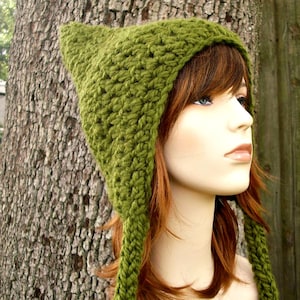 May include: A green, handmade crochet hat with pointed top and long braided ties. The hat is a solid, textured green color. The hat is shown on a mannequin with red hair.