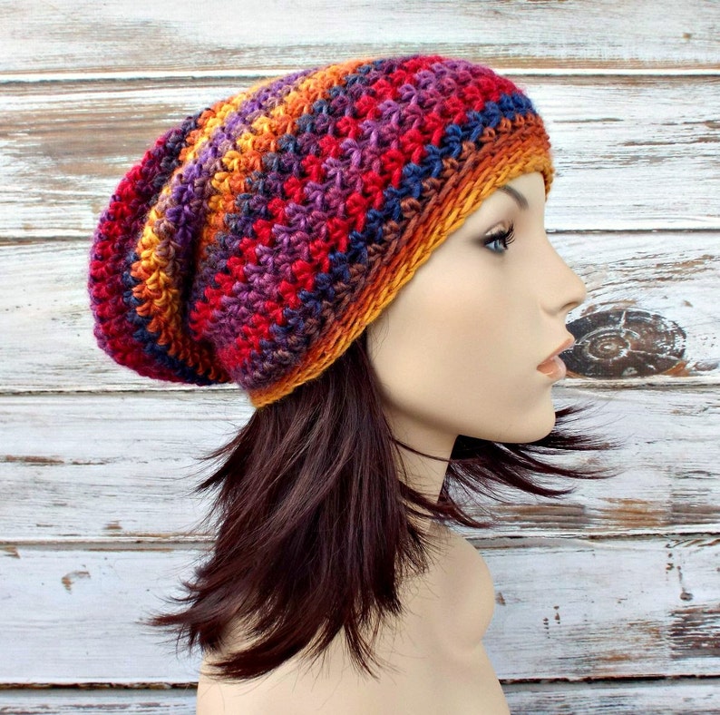 Puede incluir: Un gorro de punto de ganchillo holgado con un patr&oacute;n de degradado de colores rojo, naranja, amarillo, azul y morado.