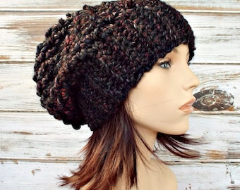Op de afbeelding: Een zwarte, rode en grijze slouchy beanie met een textuur gebreid patroon.