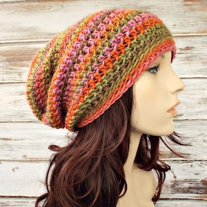 Puede incluir: Un gorro de punto de lana en crochet de estilo slouchy con un patr&oacute;n de rayas multicolor de verde, naranja, rosa y marr&oacute;n.