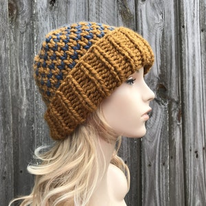 May include: A brown and blue knitted beanie with a textured pattern. The beanie is worn on a mannequin with long blonde hair.