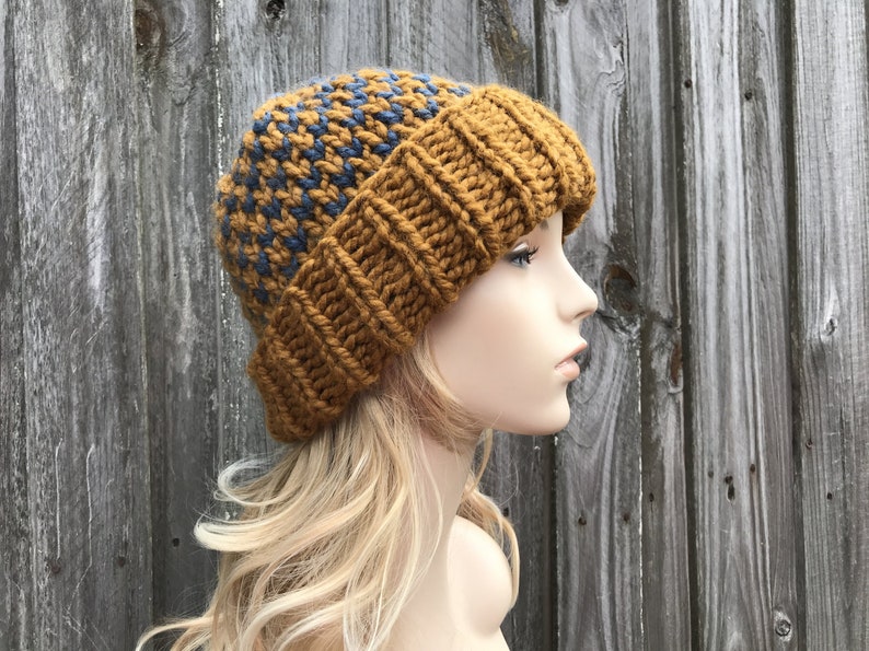 May include: A brown and blue knitted beanie with a textured pattern. The beanie is worn on a mannequin with long blonde hair.