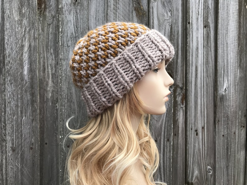May include: A knitted beanie hat with a brown and gray color block pattern. The hat is made with a chunky yarn and has a slouchy fit.