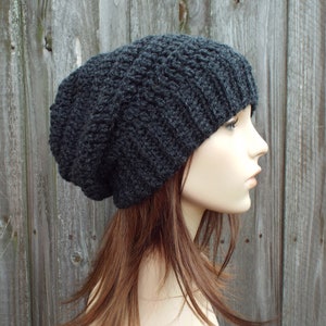 May include: A dark gray, slouchy beanie hat. The hat is made of a thick, textured yarn with a ribbed brim. The hat is shown on a mannequin head, with the side profile visible.