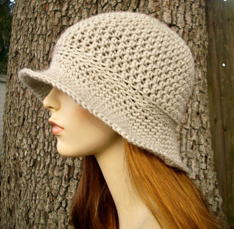 May include: A beige crocheted sun hat with a wide brim. The hat is made with a simple stitch pattern and has a slightly slouchy fit.