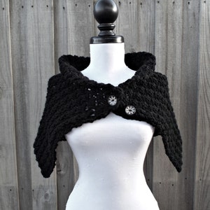 May include: Black crocheted shawl with a hooded neckline and two button closures.