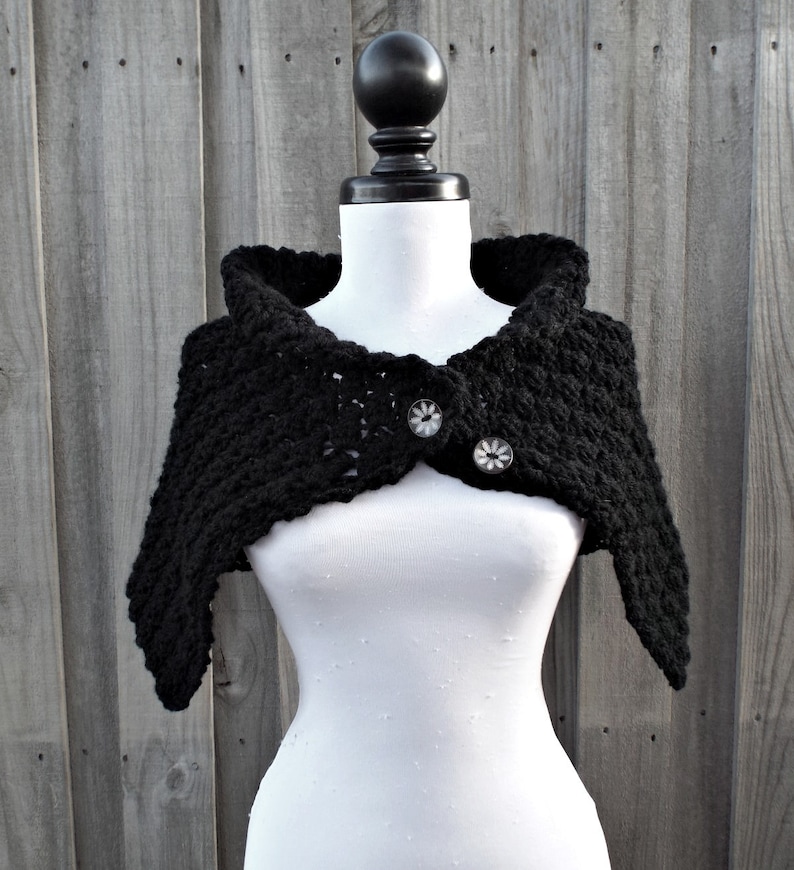 May include: Black crocheted shawl with a hooded neckline and two button closures.