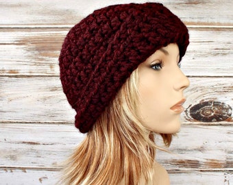 May include: A burgundy crocheted beanie hat. The hat is made with a textured stitch pattern and has a slouchy fit.